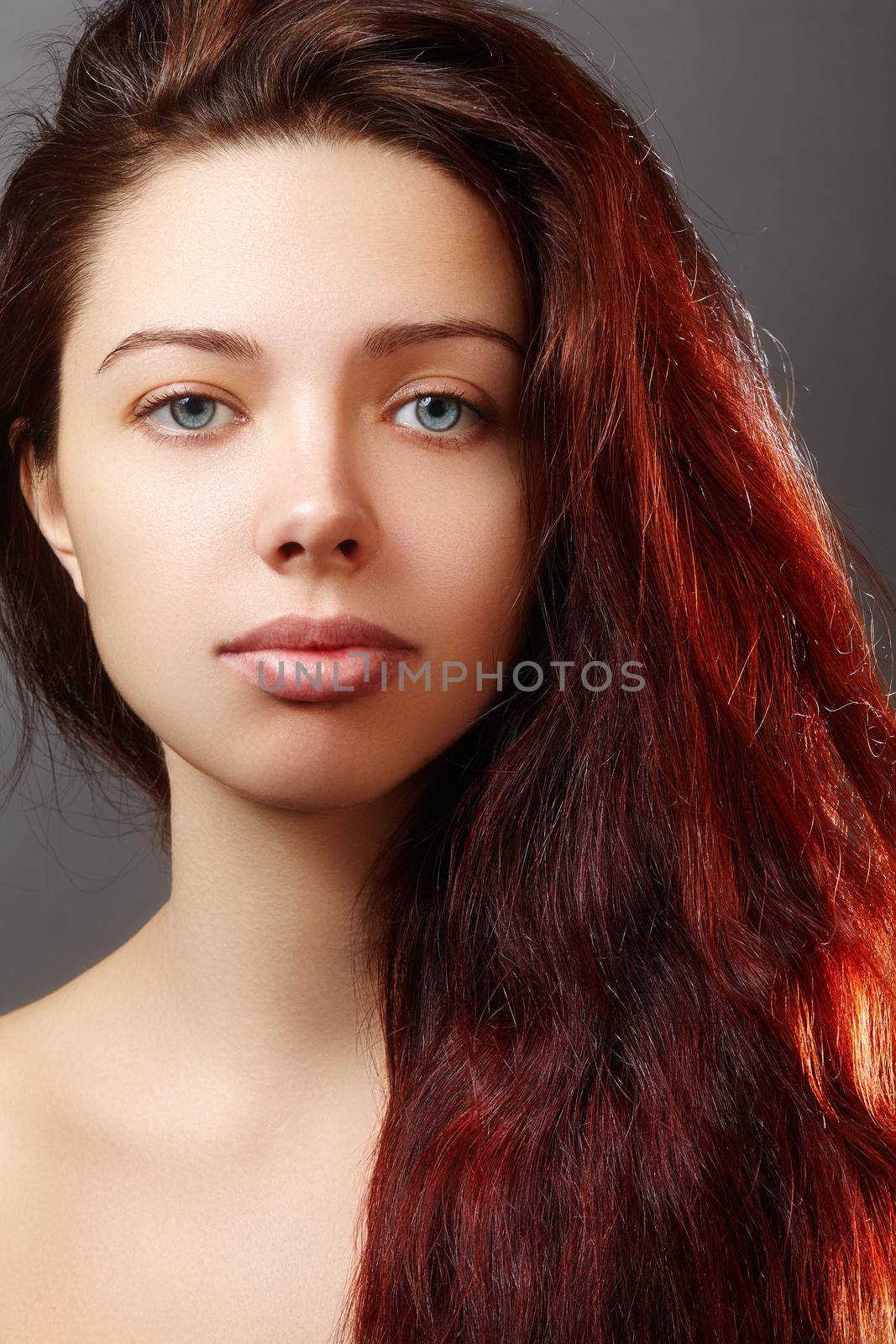 Beautiful ginger young woman with luxury hair style and fashion gloss makeup. Beauty portrait of sexy model with red hair. Long soft shiny hairstyle. Close-up studio shot of look redhead girl