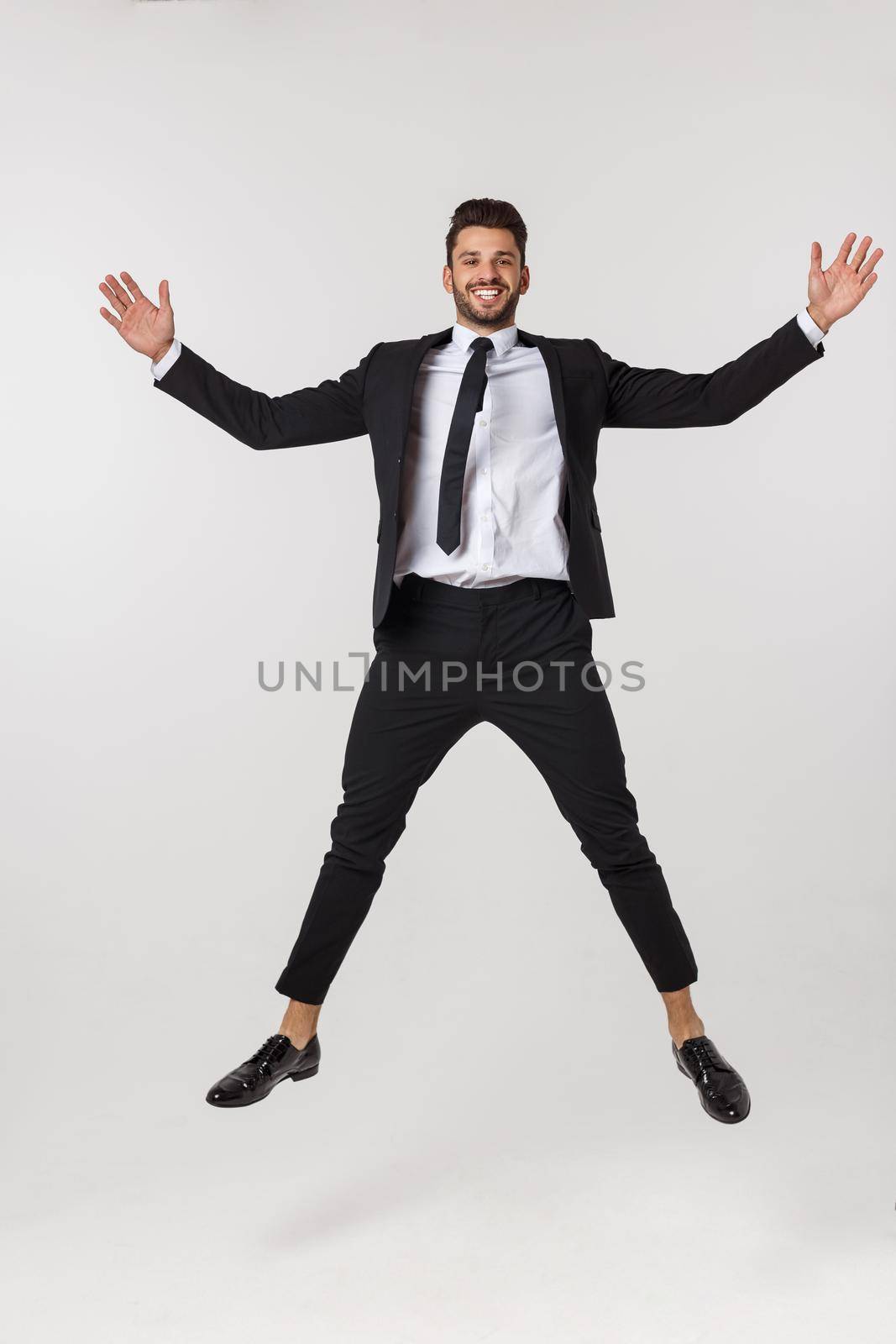 Portrait of a happy businessman jumping in air against isolated white background