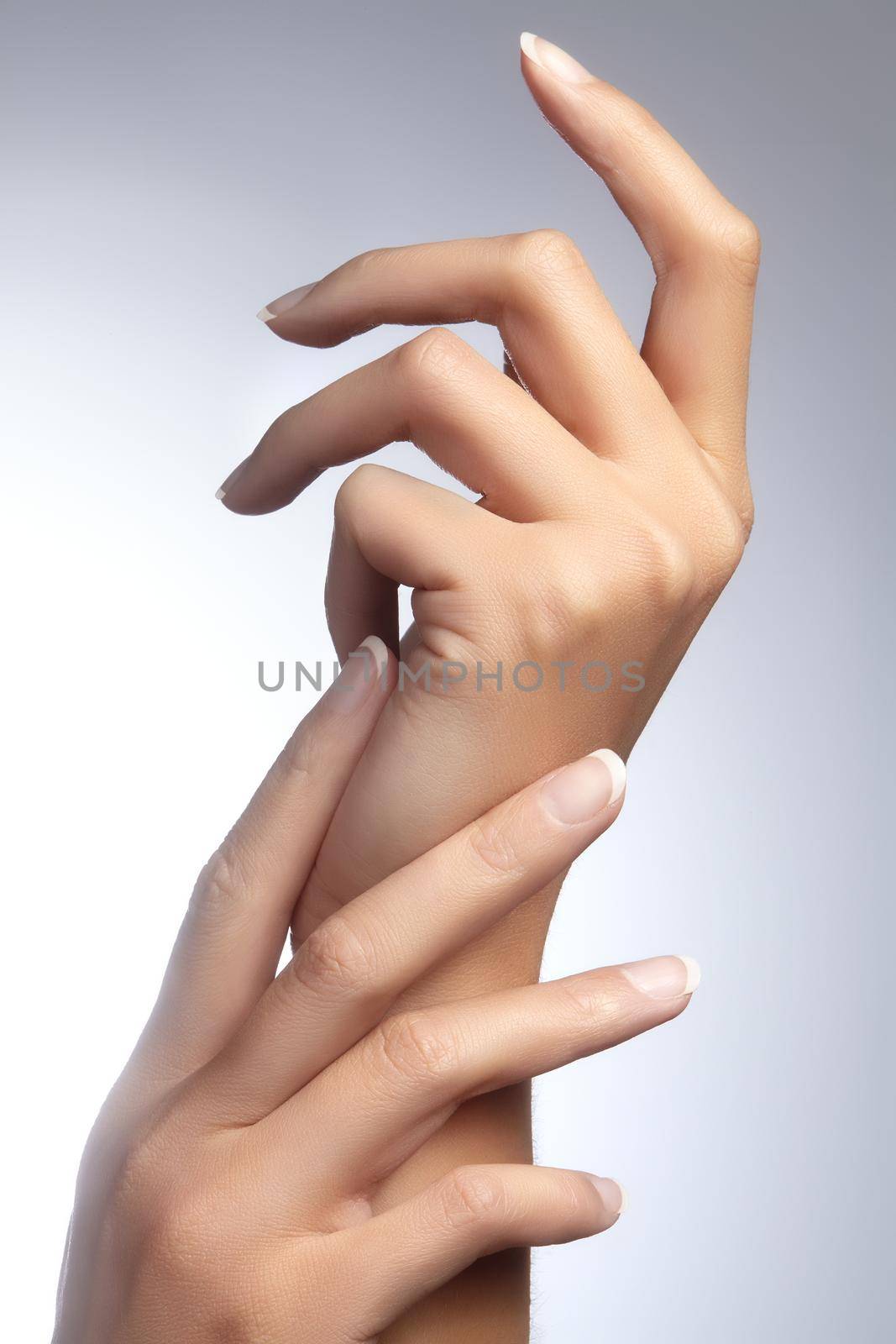 Beautiful woman's hands on light background. Care about hand. Tender palm with natural manicure, clean skin. French nails