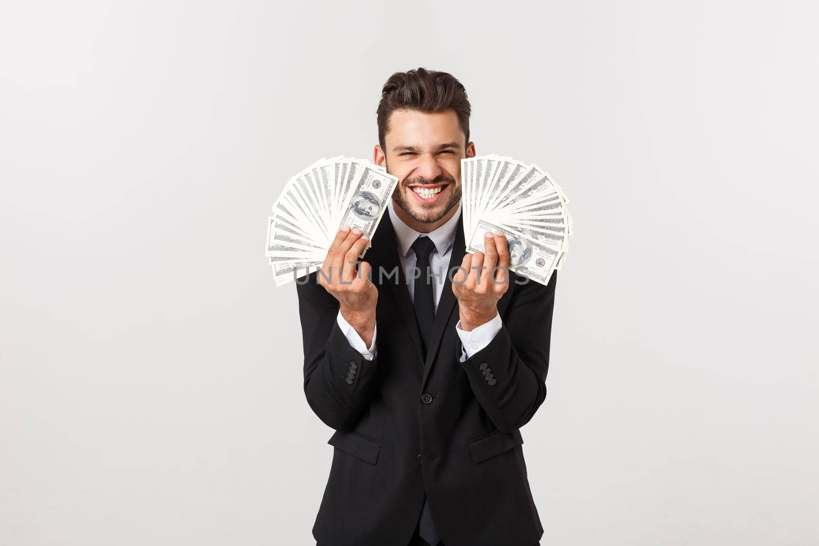 Portrait of a satisfied young businessman holding bunch of money banknotes isolated over white background