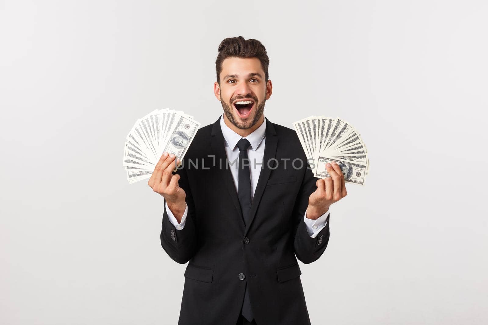 Portrait of a satisfied young businessman holding bunch of money banknotes isolated over white background