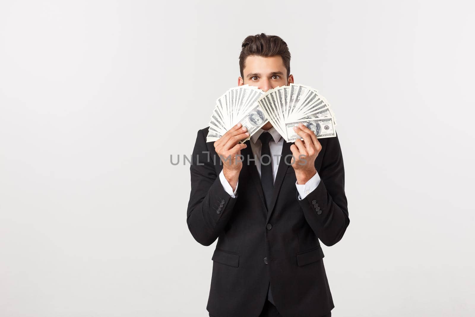 Portrait of a satisfied young businessman holding bunch of money banknotes isolated over white background