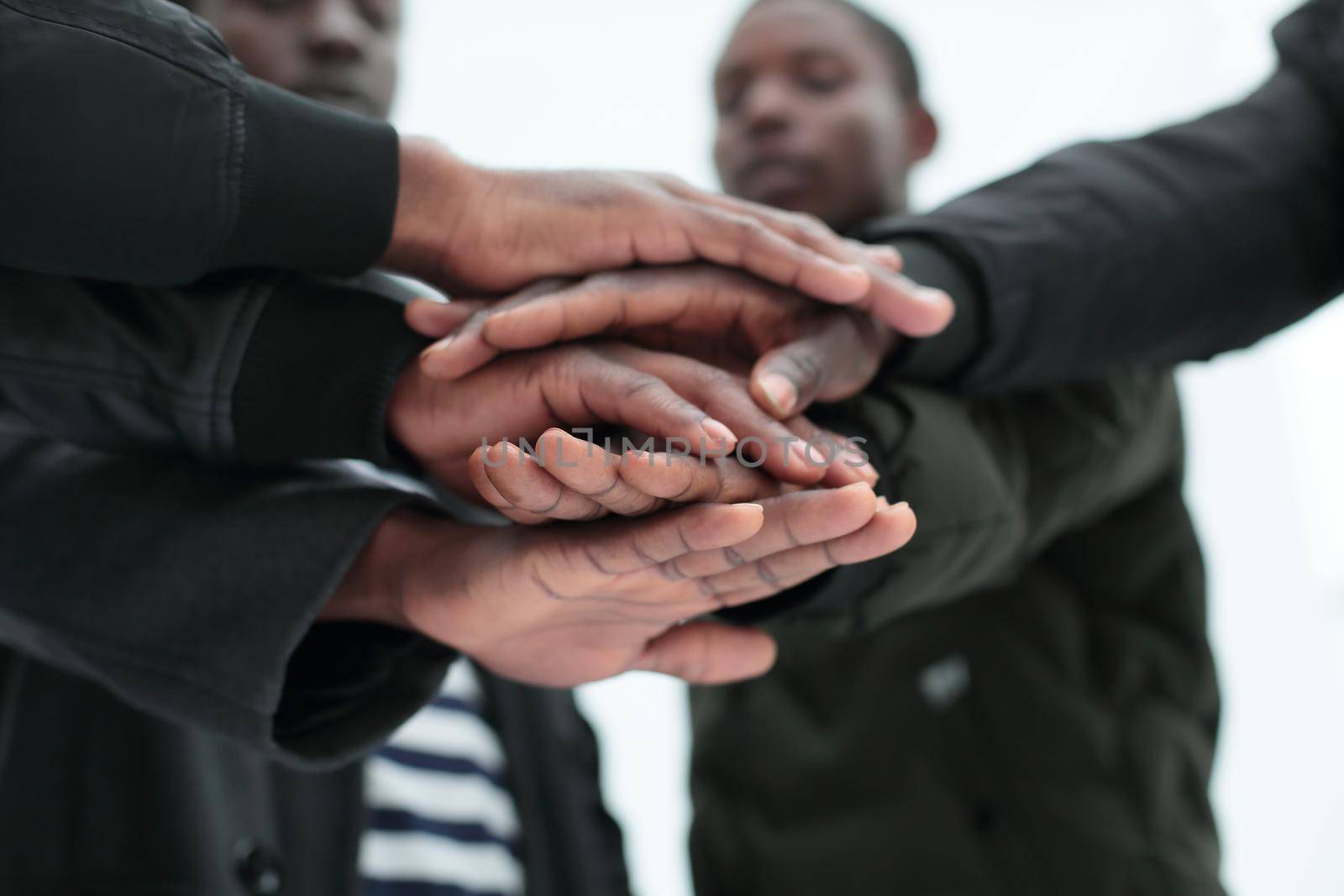 close up. a group of friends putting their hands together. isolated on white