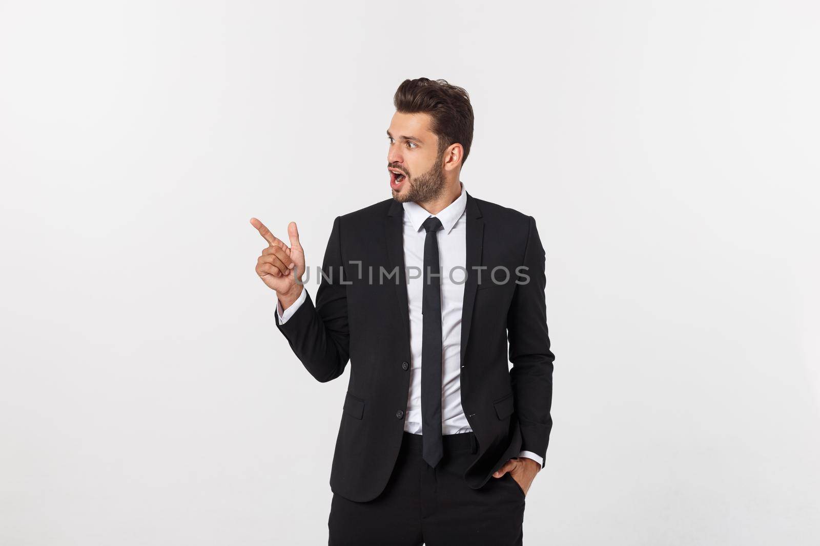 Portrait of young business man in suit pointing at copy space over white background