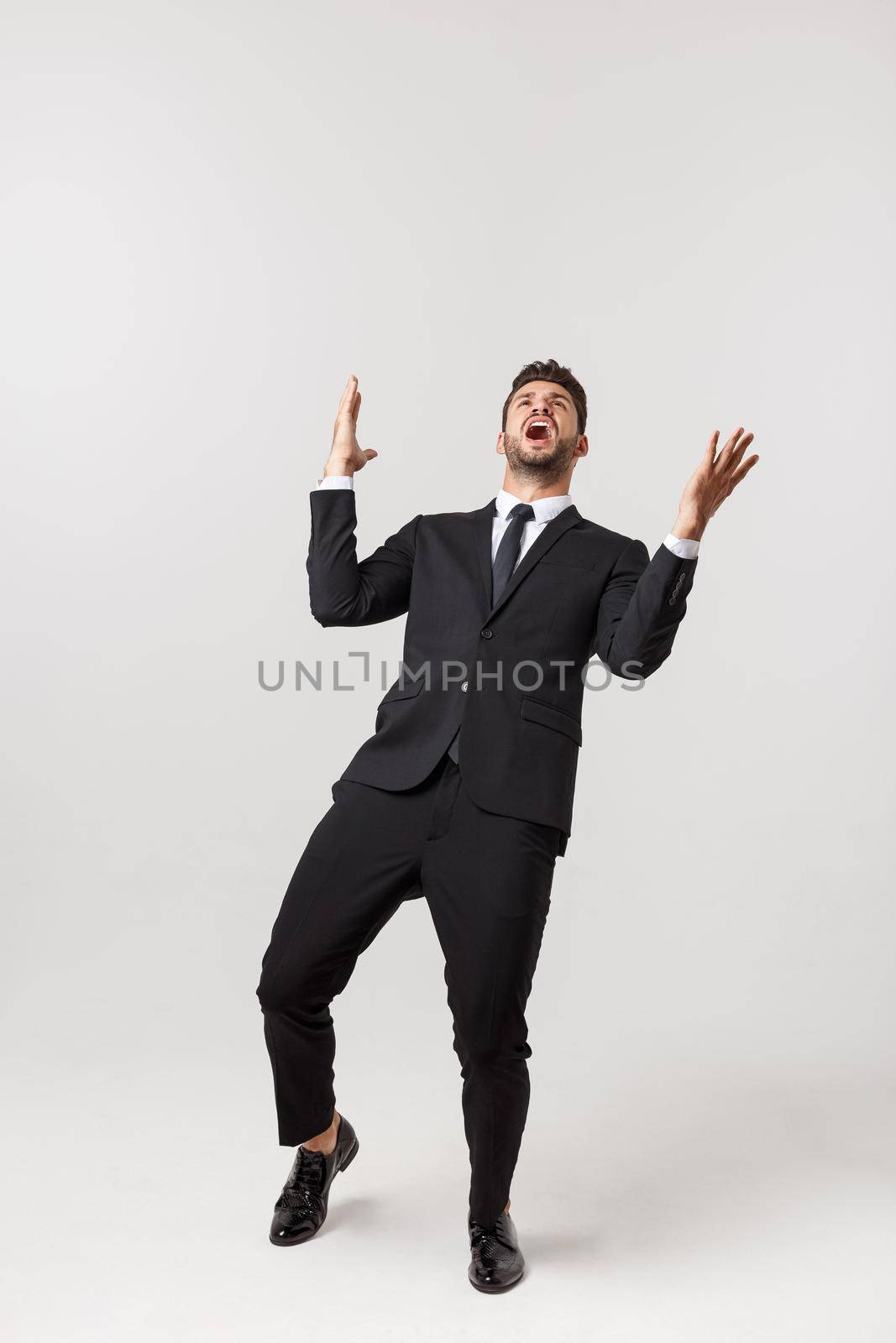 Cheerful young bearded business man show hand up excited with clenched fists. Full length portrait business man isolated over white studio background by Benzoix