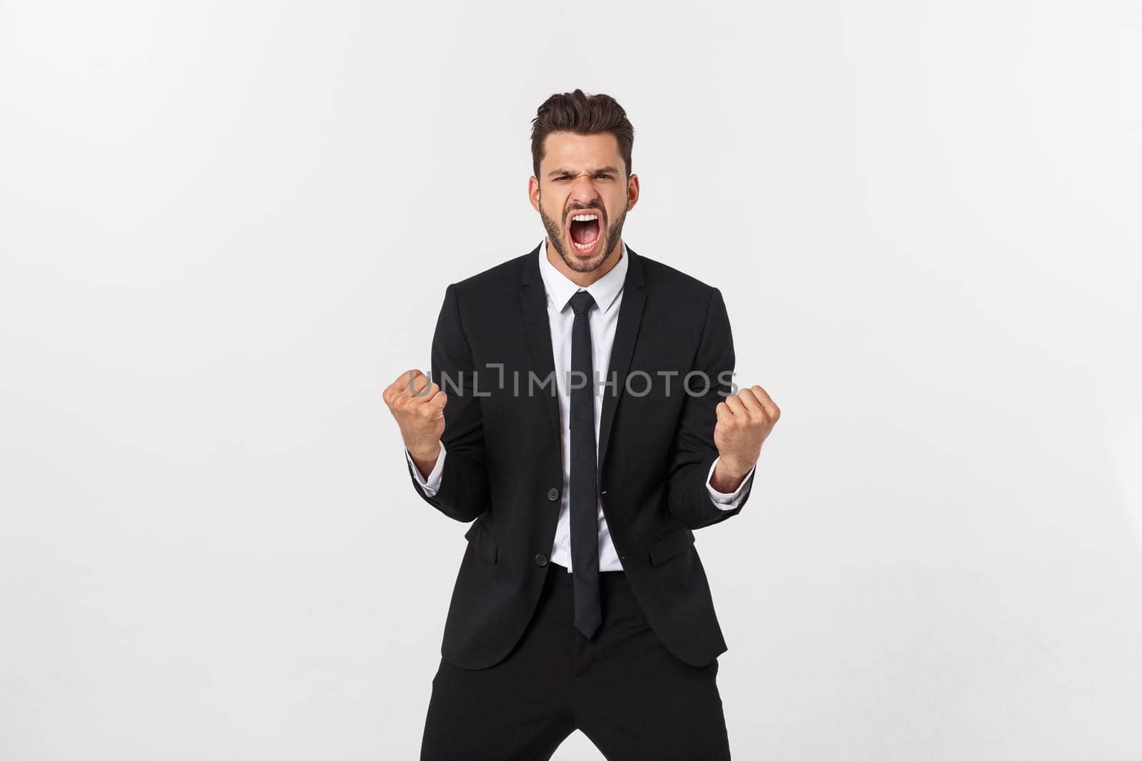 Young businessman celebrating his success over gray background