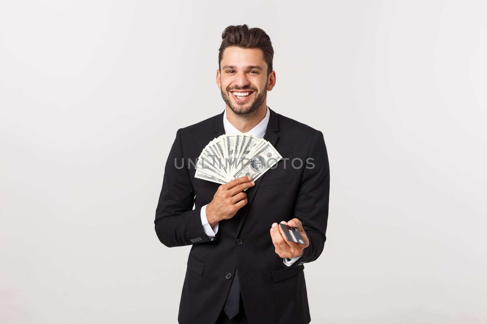 Portrait of a happy smiling man holding bunch of money banknotes and showing credit card isolated over white background