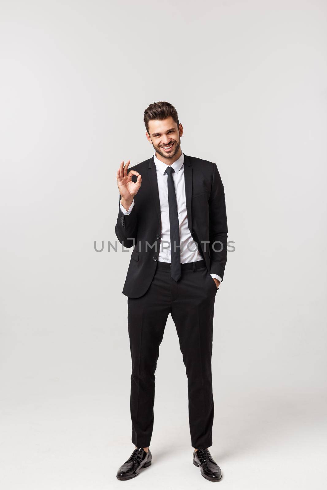 Full length of happy employee showing okay sign hand gesture isolated on white background.