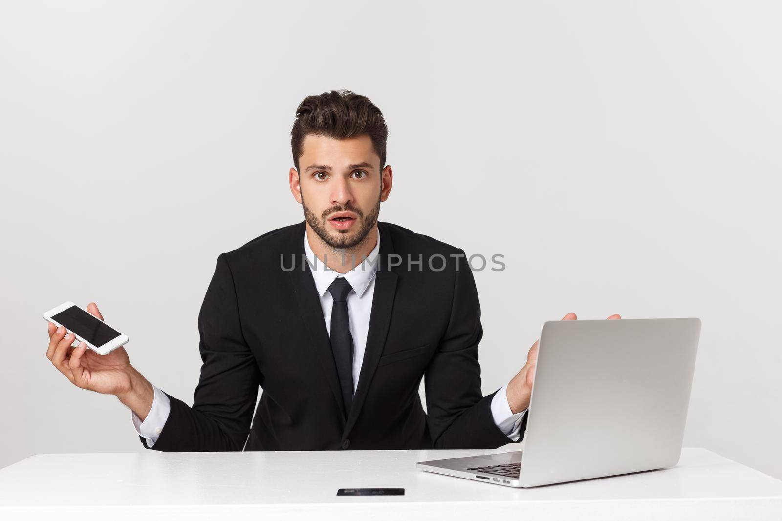 Caucasian attractive businessman worried and tired talking on mobile phone sitting at office desk working in stress overworked and frustrated