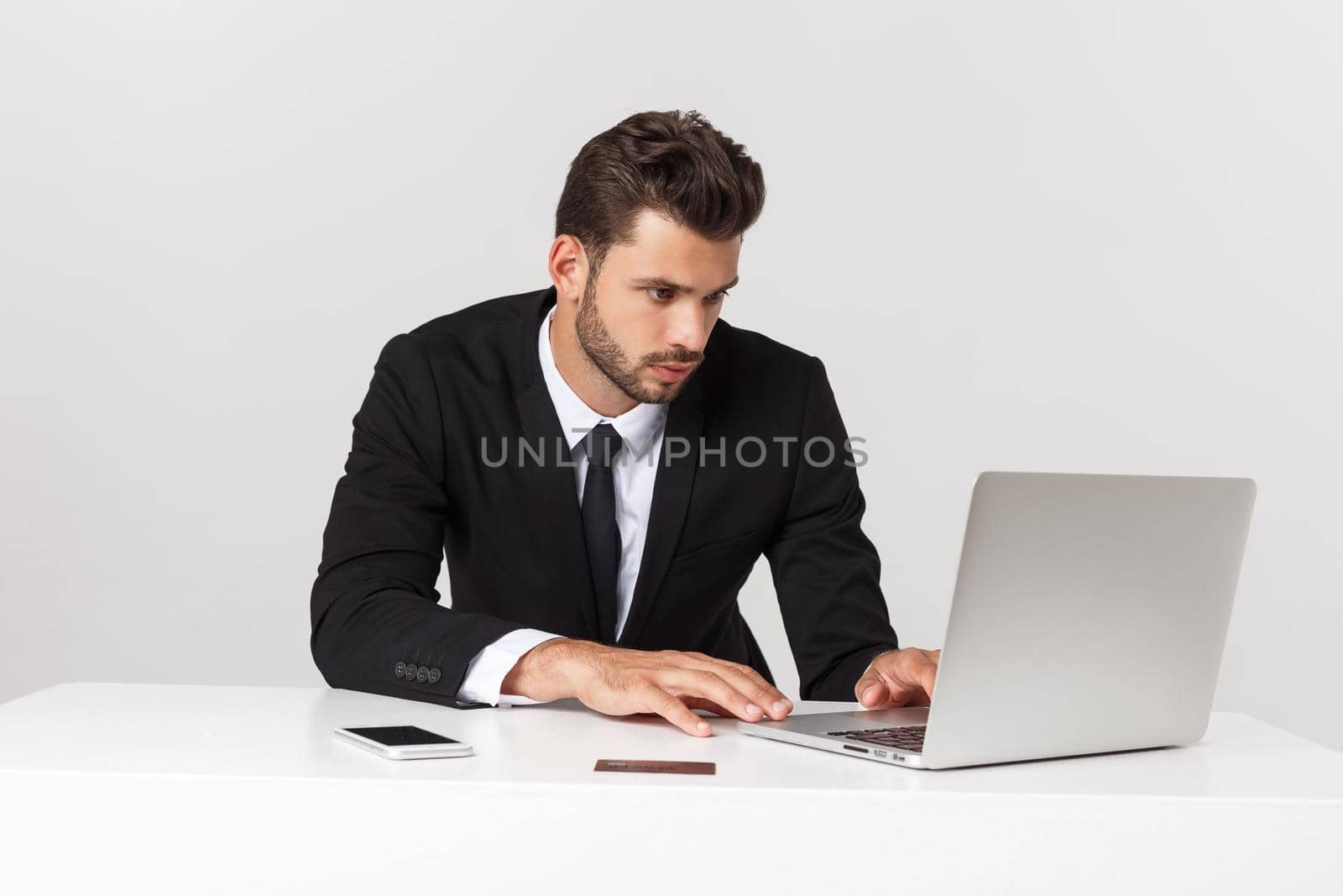 Serious handsome businessman working in the office,front view with laptop, isolated on white