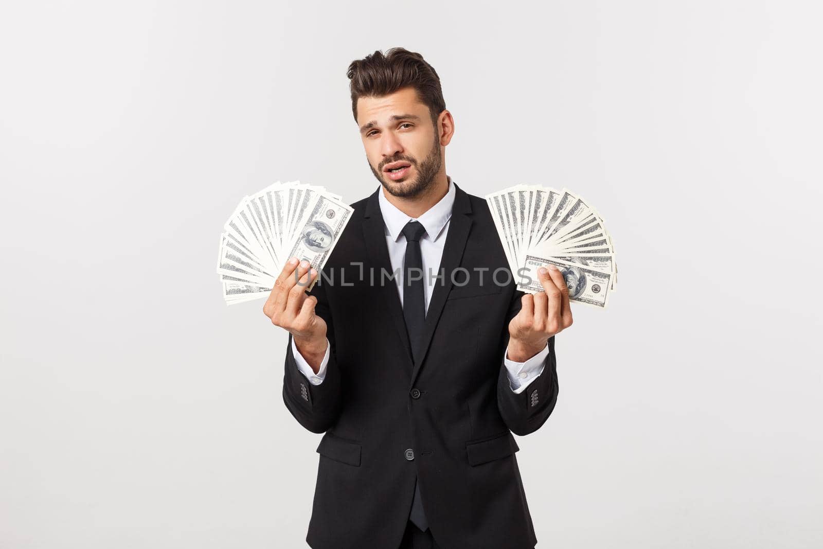 Portrait of a satisfied young businessman holding bunch of money banknotes isolated over white background