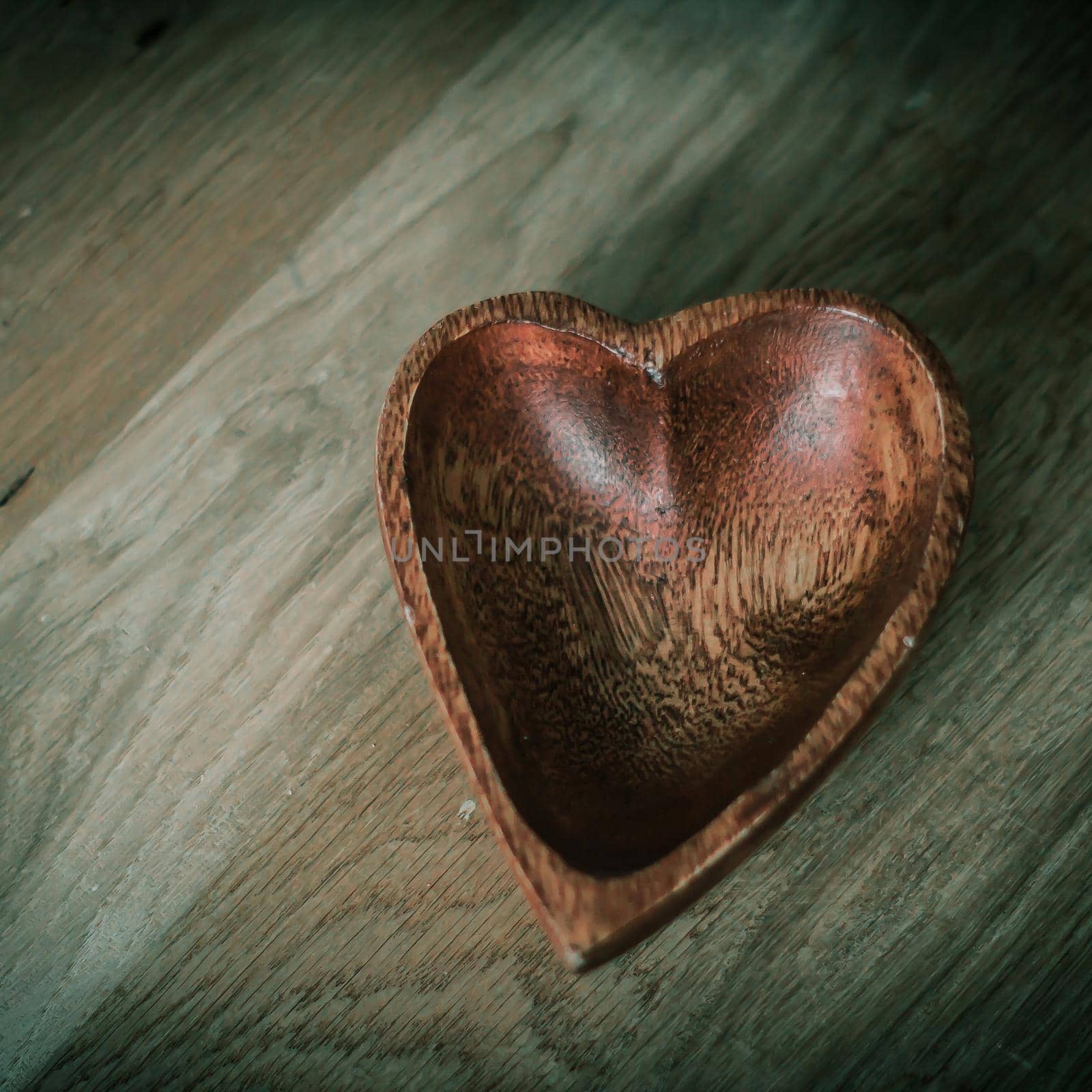 wooden salad bowl in the shape of heart on wooden background