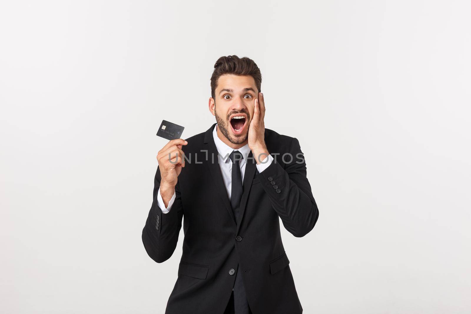 Surprised, speechless and impressed handsome caucasian businessman in classic suit showing credit card, say wow, standing white background astonished by Benzoix