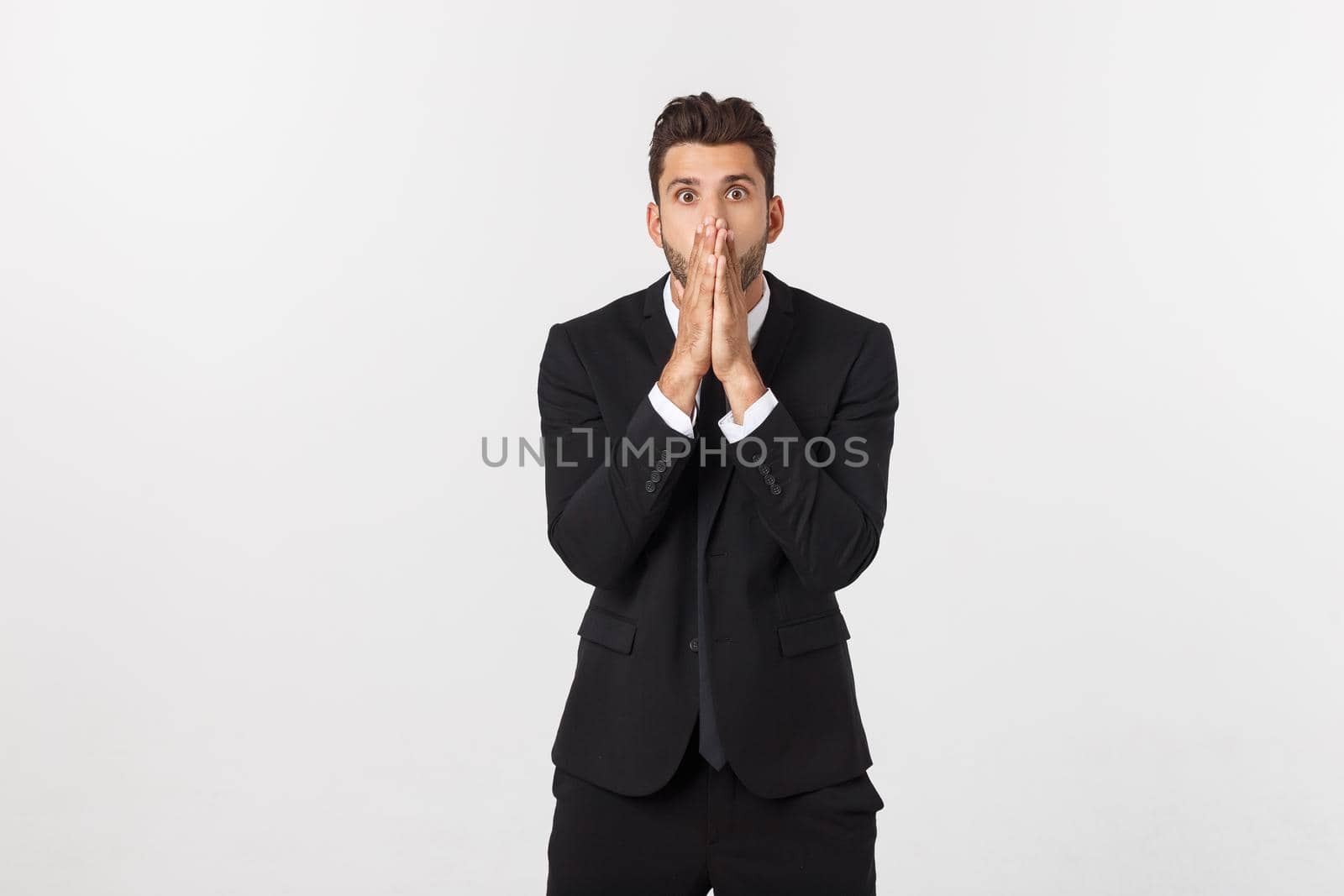 Well dressed man in the studio emphasize thoughtful thinking, think carefully and try to choose to hold hands and stand against the white background