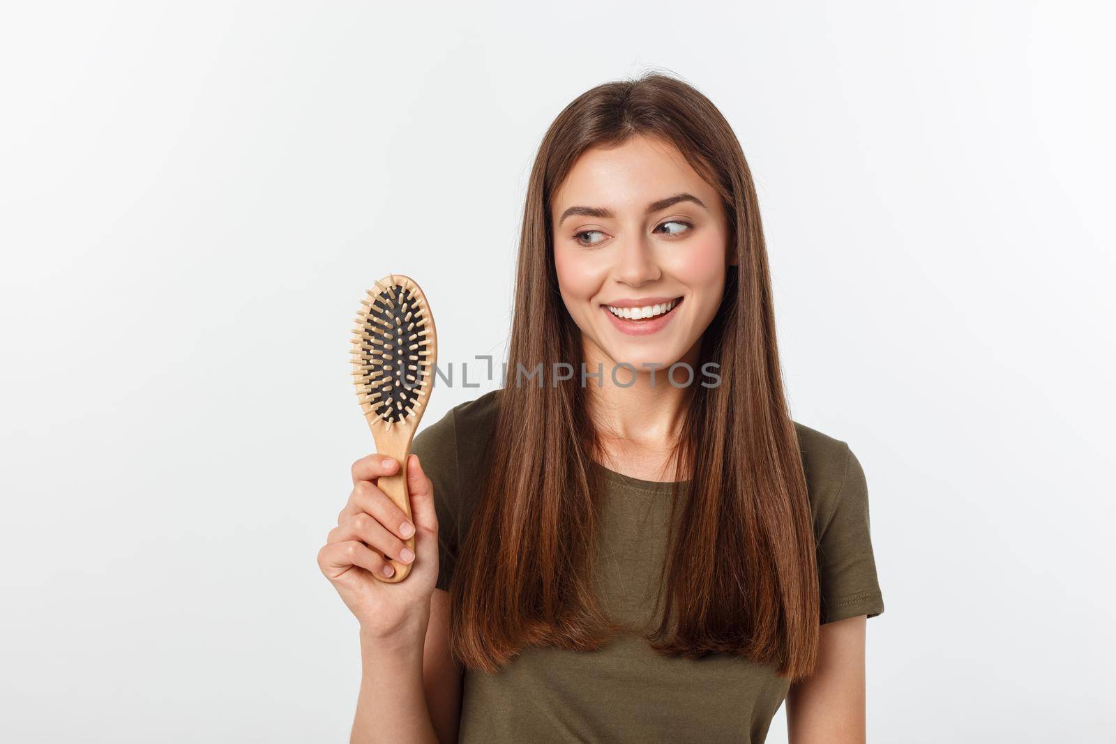 Happy young woman combing her long healthy hair on white background