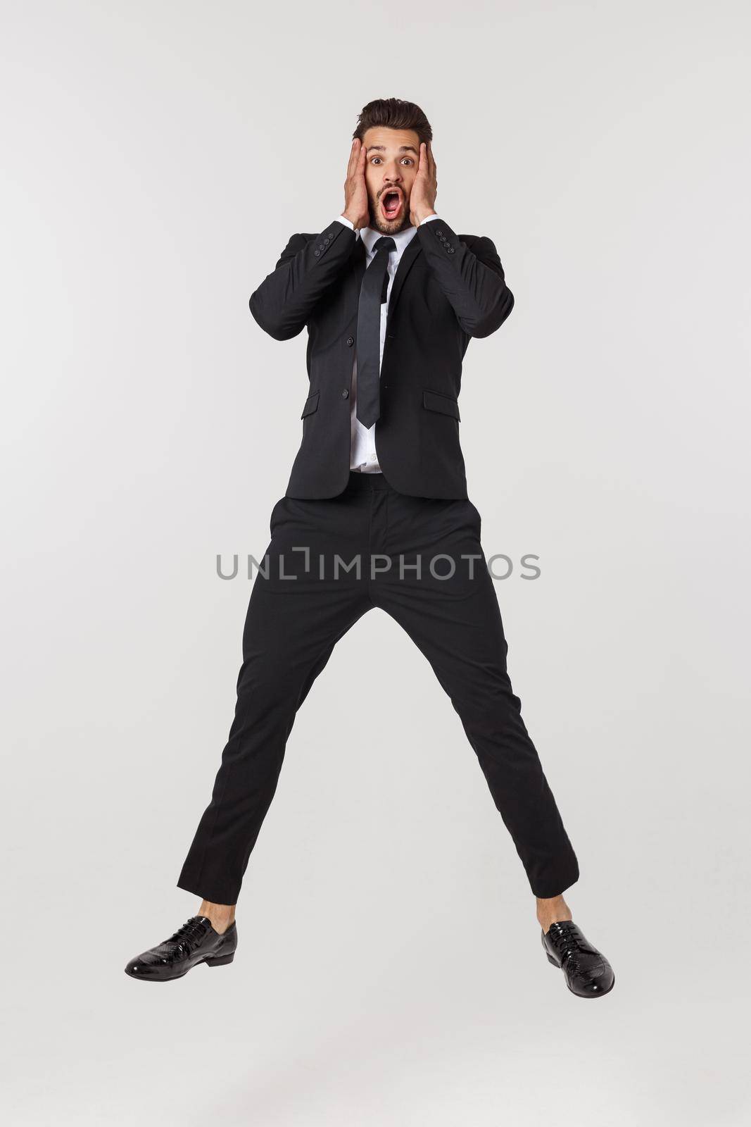Portrait of a happy businessman jumping in air against isolated white background