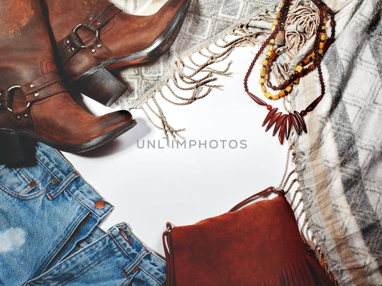 Boho Style. Leather Boots, Wooden Necklace, Denim Shorts and Hippie Bag with Fringe on White Background. Overhead View of Woman's Casual Day Outfits. Trendy Hipster Look.