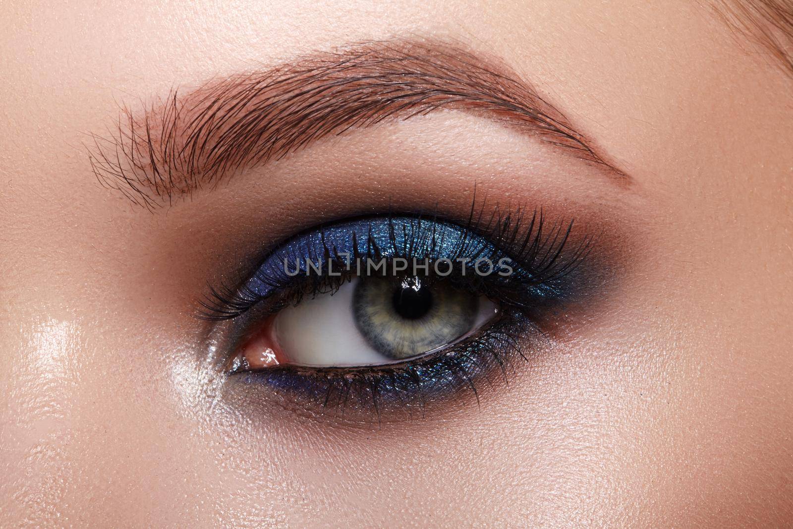 Closeup Macro of Woman Face with Green Eyes Make-up. Fashion Indigo Celebrate Makeup, Glowy Clean Skin, perfect Shapes of Brows. Shiny Shimmer