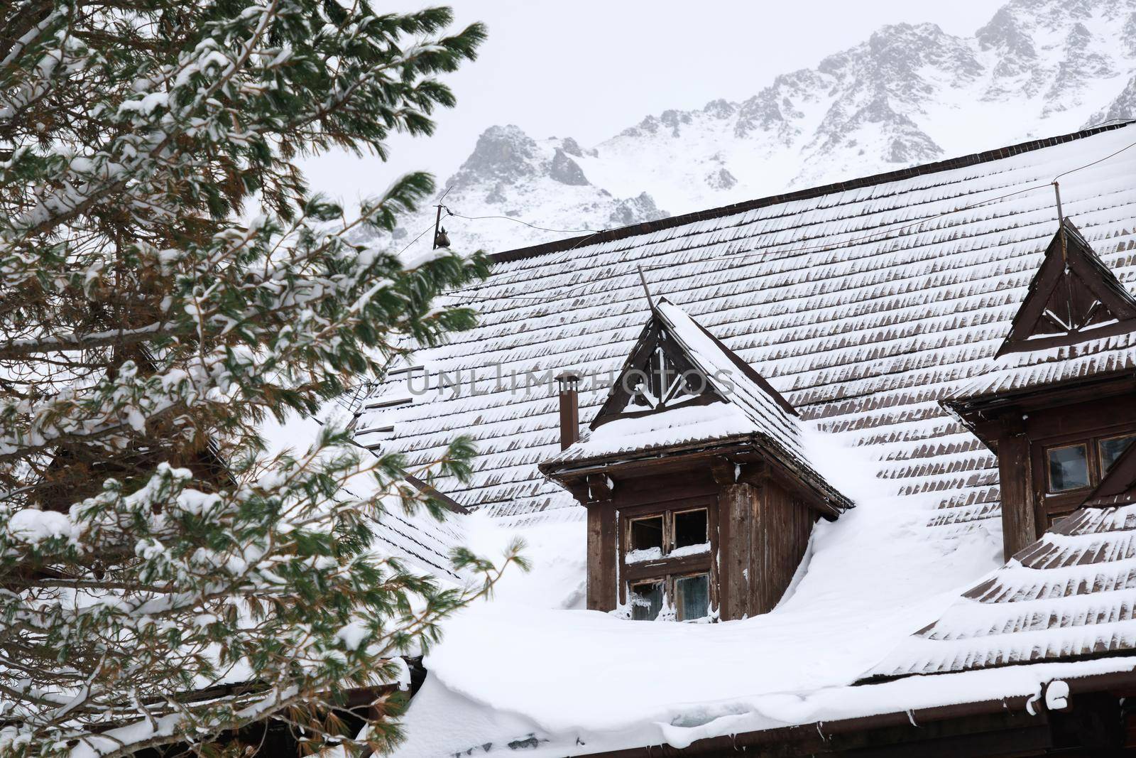 The snow-covered roof of the old wooden house in mountains