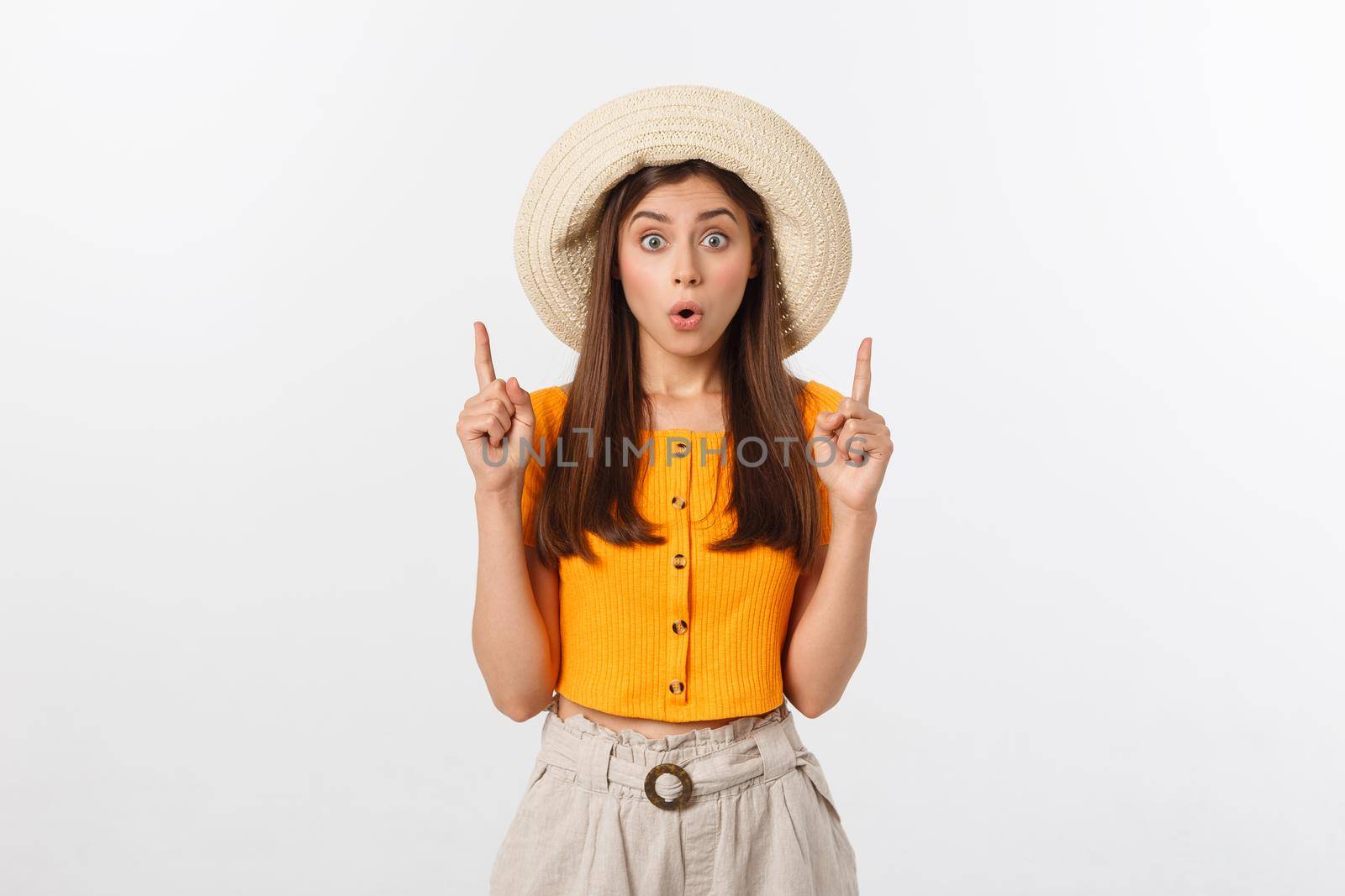 Teenager girl on summer vacation surprised and pointing finger on copy space over isolated white background