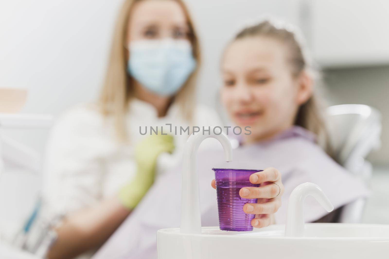 Close-up of a teenager girl  holding disposable water cup for mouthwash at the dentist. 