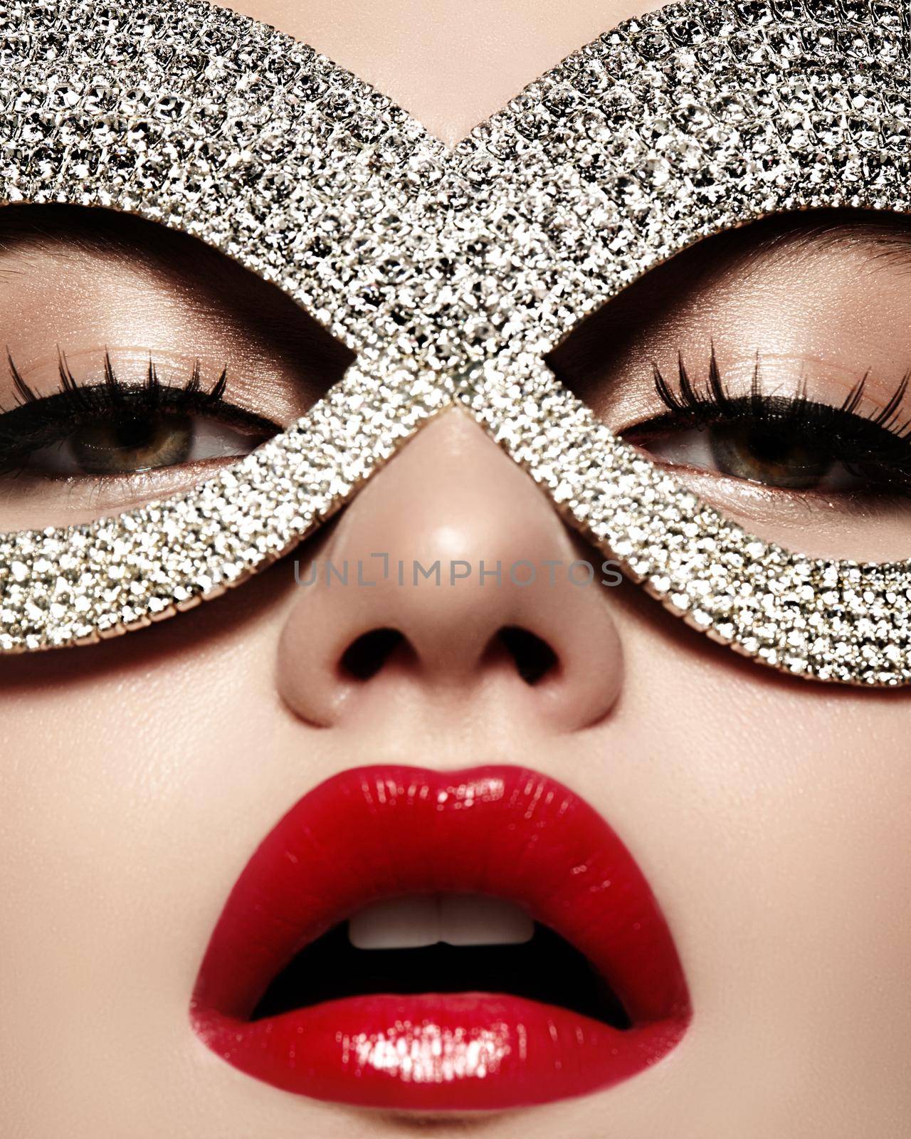 Beautiful Model with Fashion luxe Lips Make-up wearing bright brilliant mask. Masquerade style woman. Holiday celebration look