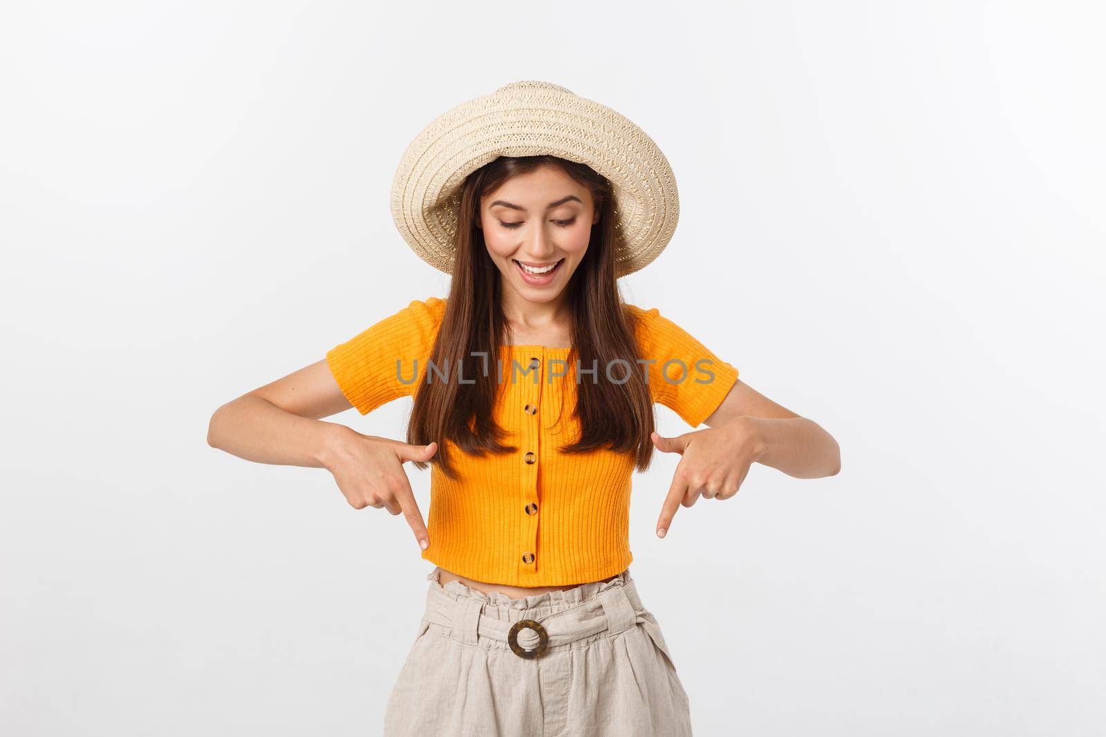 Teenager girl on summer vacation surprised and pointing finger on copy space over isolated white background