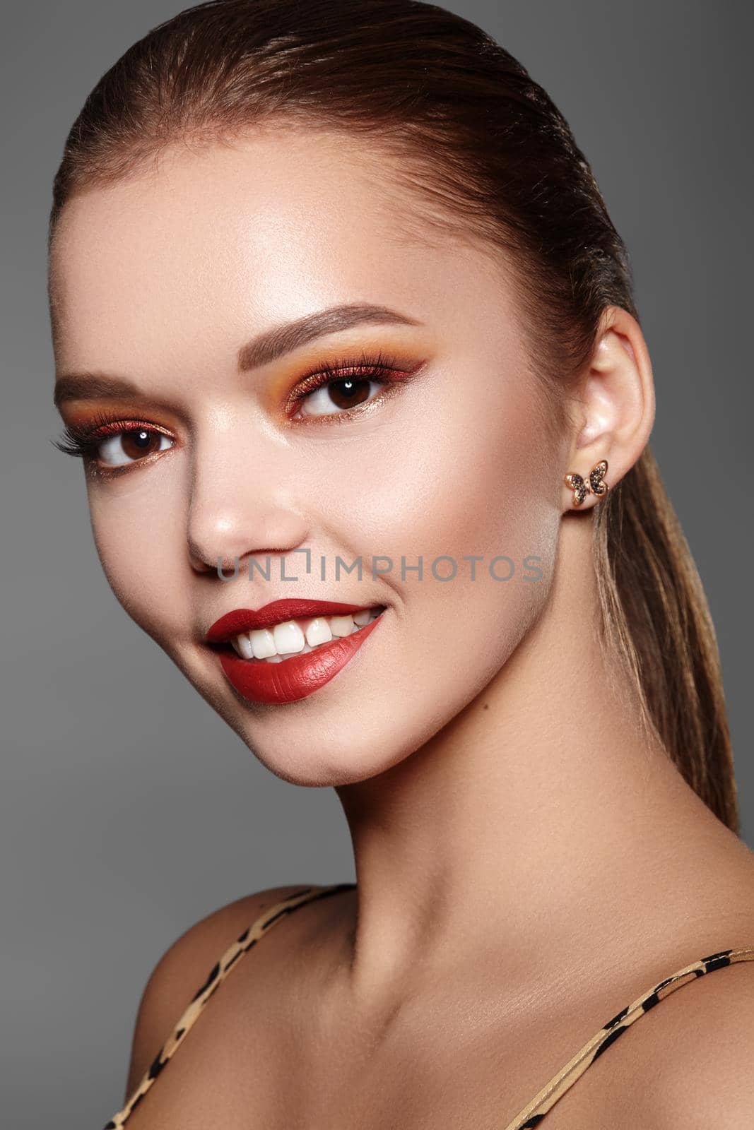 Beautiful Woman with Professional Makeup. Party Gold Eye Make-up, Perfect Eyebrows, Shine Skin. Bright Fashion Look with Red Lips