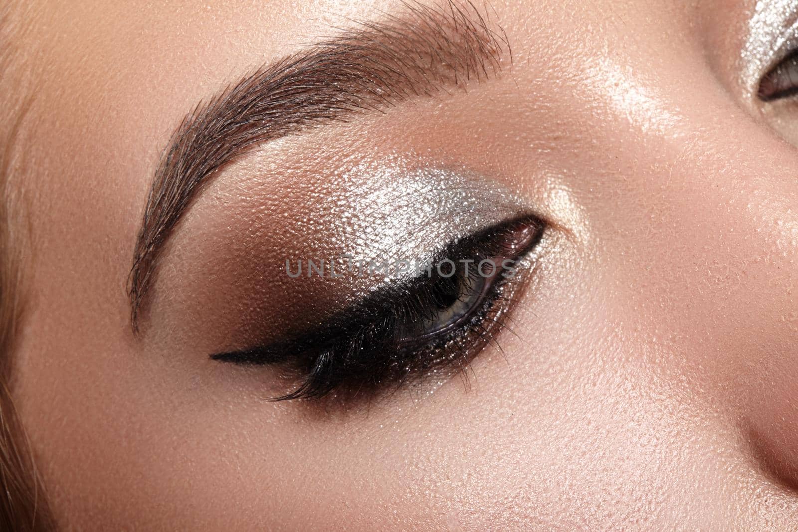 Beautiful Woman with Professional Makeup. Closeup Macro of Woman Face with Cat-Eye Make-up. Fashion Celebrate Makeup, Perfect Eyebrows, Glowy Clean Skin, perfect Shapes of Brows. Shiny Shimmer