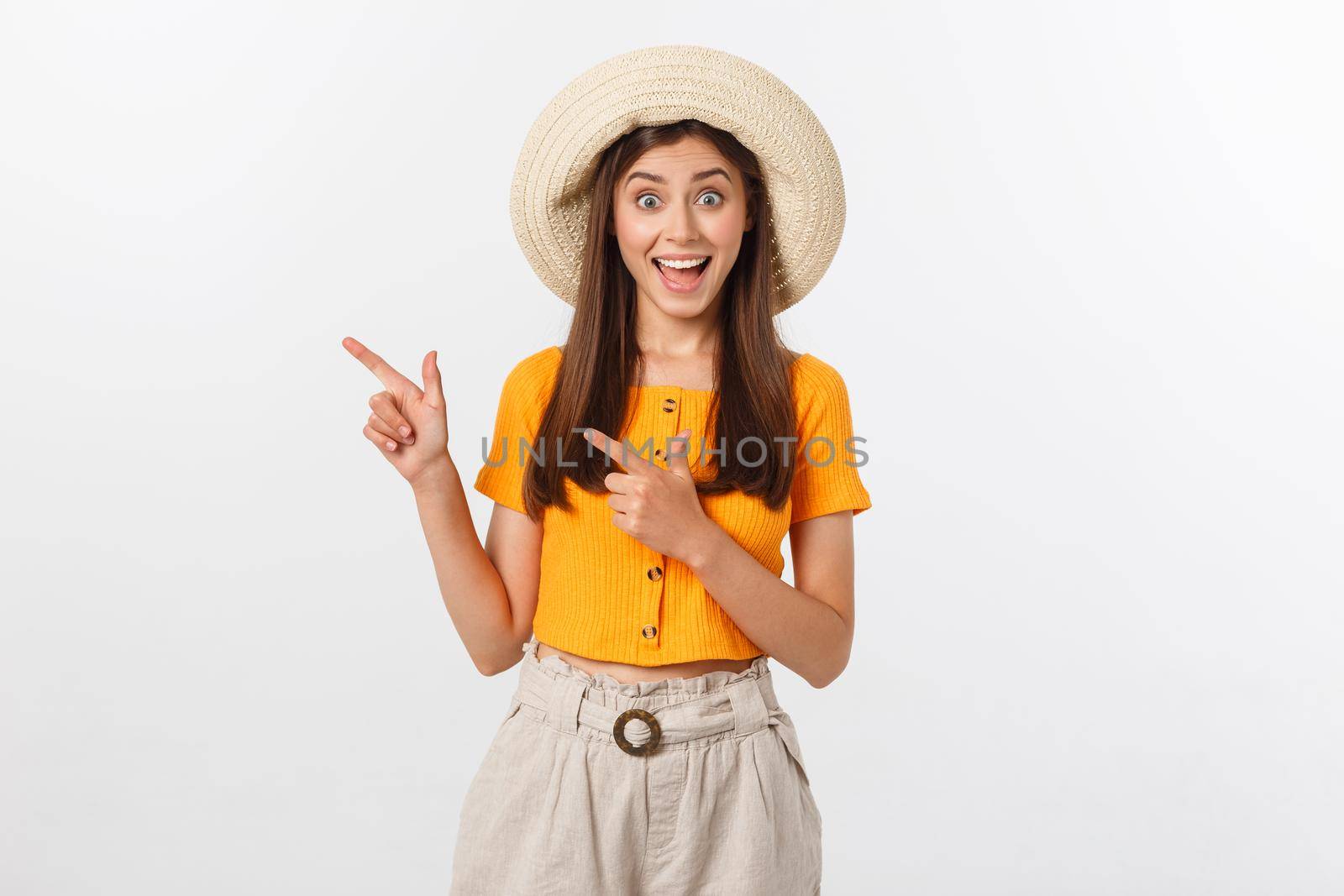 Teenager girl on summer vacation surprised and pointing finger on copy space over isolated white background. by Benzoix