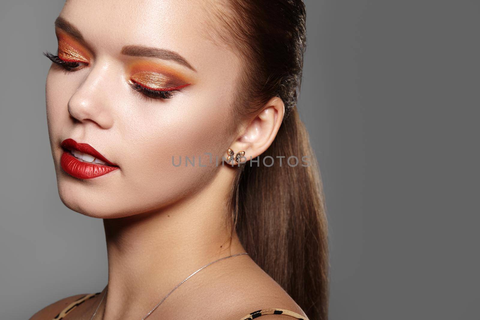 Closeup portrait of Woman Face with Gold glitter Make-up, bright red liner on Eyes. Fashion Celebrate Makeup, Glowy Skin. Shiny Simmer and metalic eye shadows