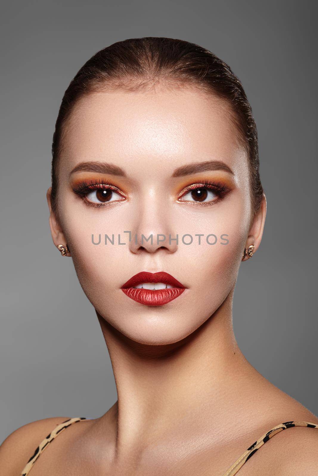 Beautiful Woman with Professional Makeup. Party Gold Eye Make-up, Perfect Eyebrows, Shine Skin. Bright Fashion Look with Red Lips