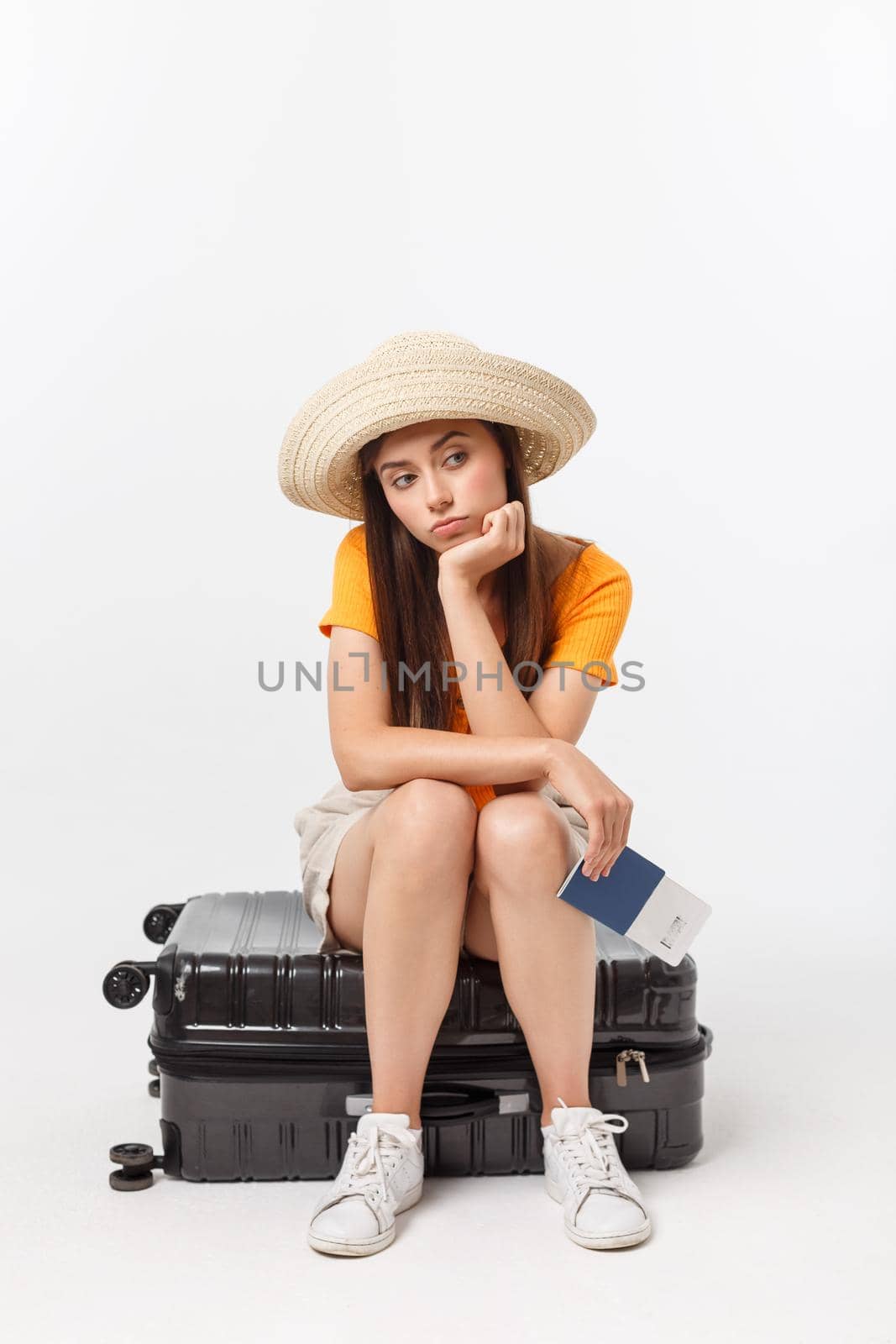 Lifestyle and travel Concept: Young beautiful caucasian woman is sitting on suitecase and waiting for her flight.Isolated over white background.