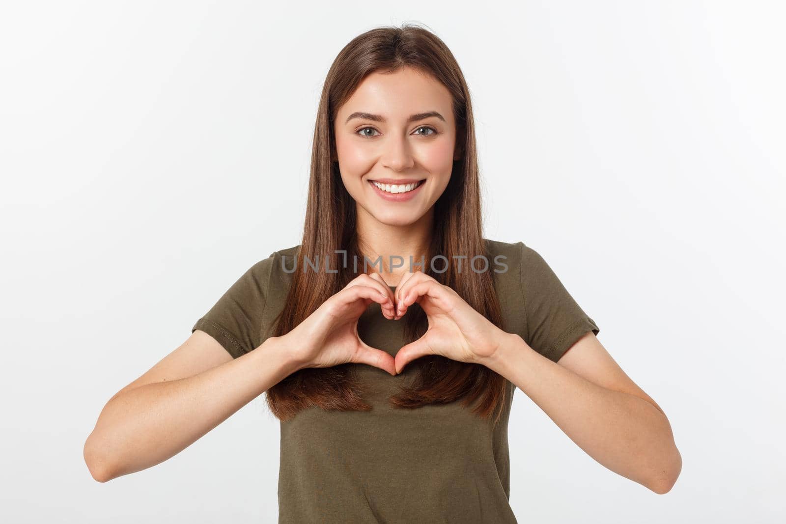 Smiling teenager girl making heart shape with her hands isolated on white