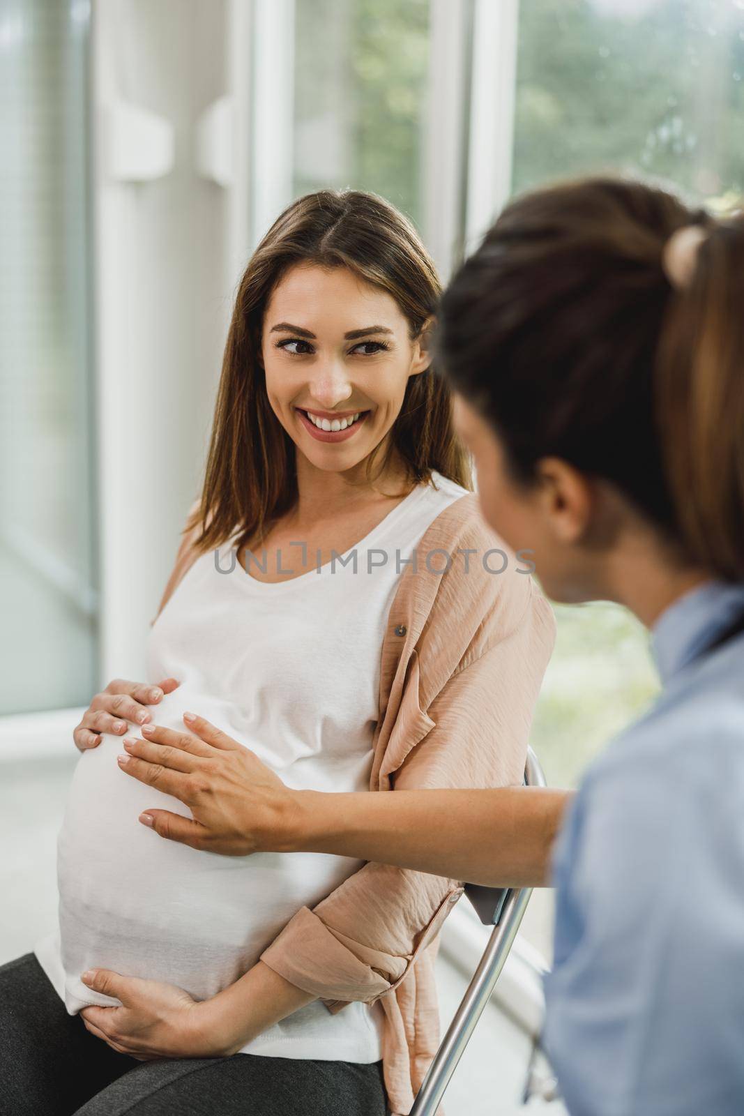 Pregnant Woman Talking To Gynecology Nurse At Waiting Room by MilanMarkovic78