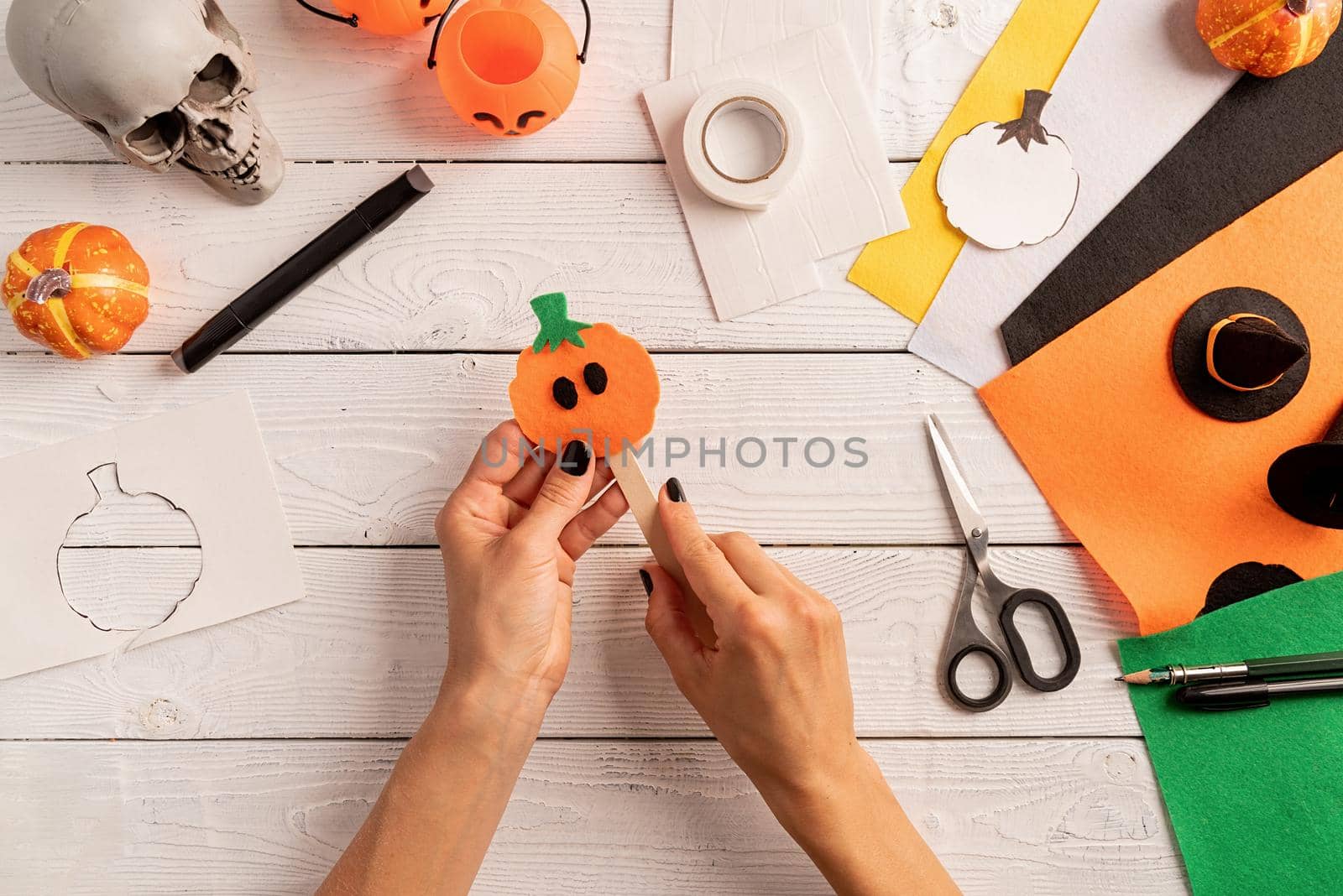 Happy Halloween concept. Step by step instruction of making halloween bookmark DIY pumpkin craft. Step 6 - stick a pumpkin and the ice cream stick. Bookmark is ready. Top view flat lay