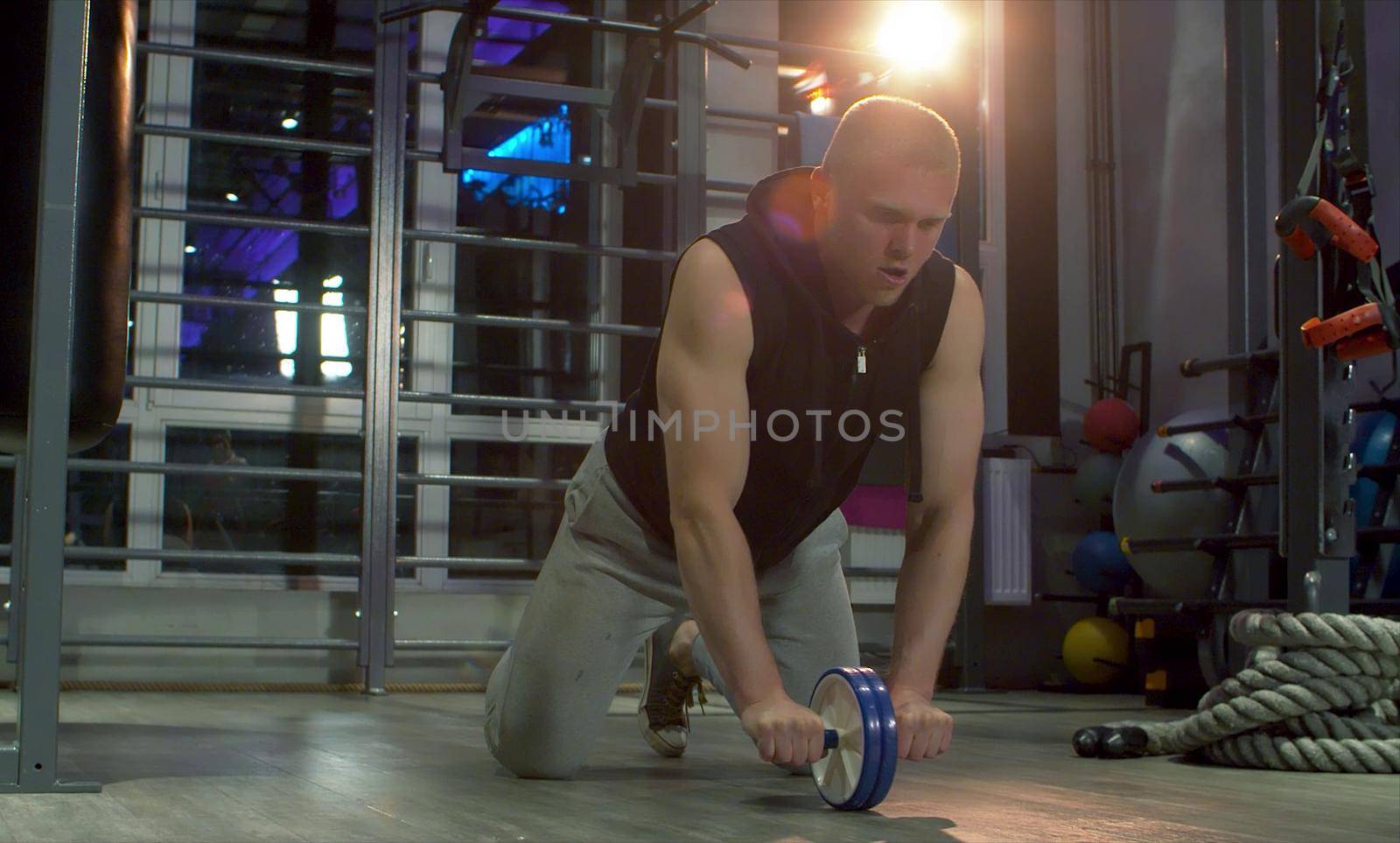Man athlete doing exercise with ab wheel by Chudakov