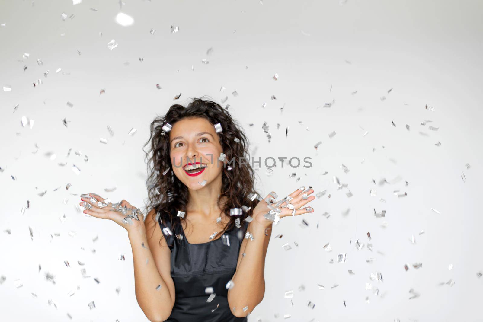 The emotion of success. Happy sexy brunette girl is enjoying celebrating with confetti on a white background by Try_my_best