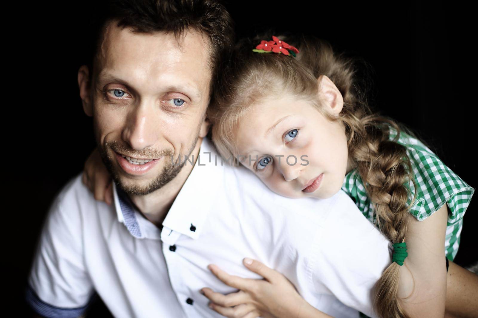 concept of trust -a little pretty daughter hugging her beloved father .photo on a dark background.