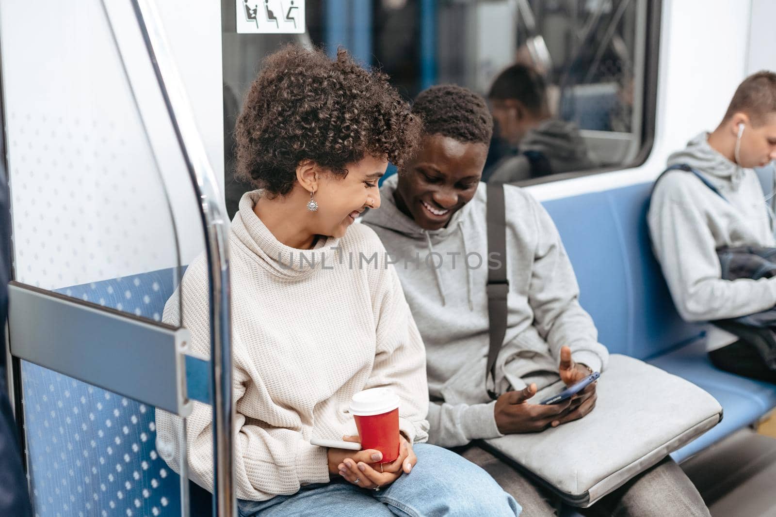 young couple using a smartphone while sitting in a subway car . by SmartPhotoLab