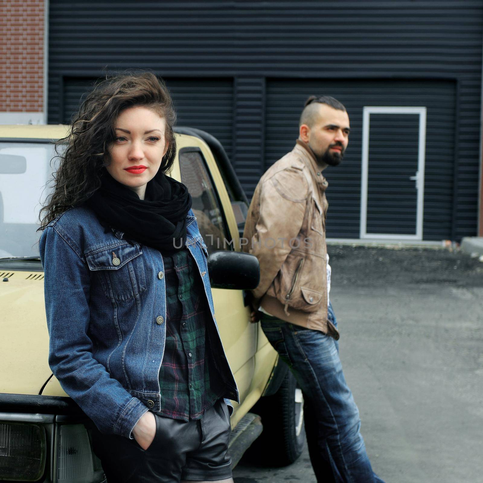 young woman and her boyfriend standing near the car . the concept of the relationship