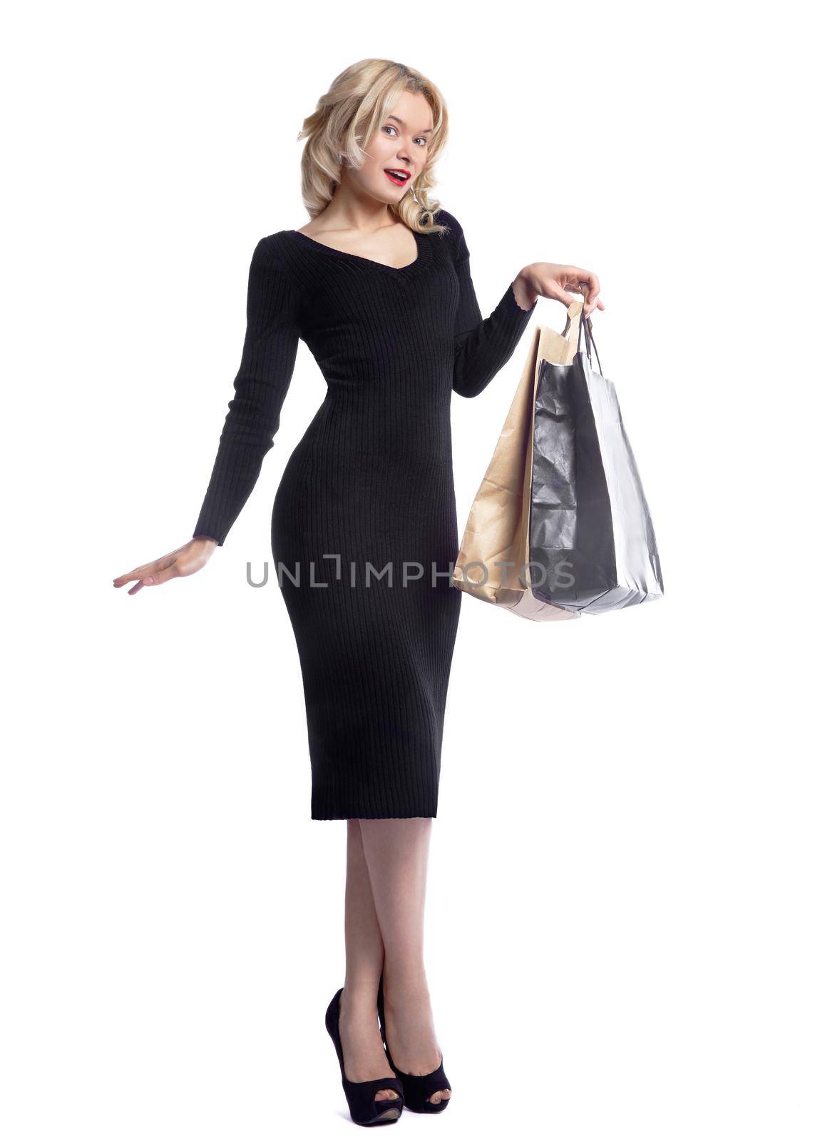 Shopping young woman holding bags isolated on white studio background. Love fashion and sales. Happy blond girl in black luxury glomour dress, shopper with handbags and gifts.
