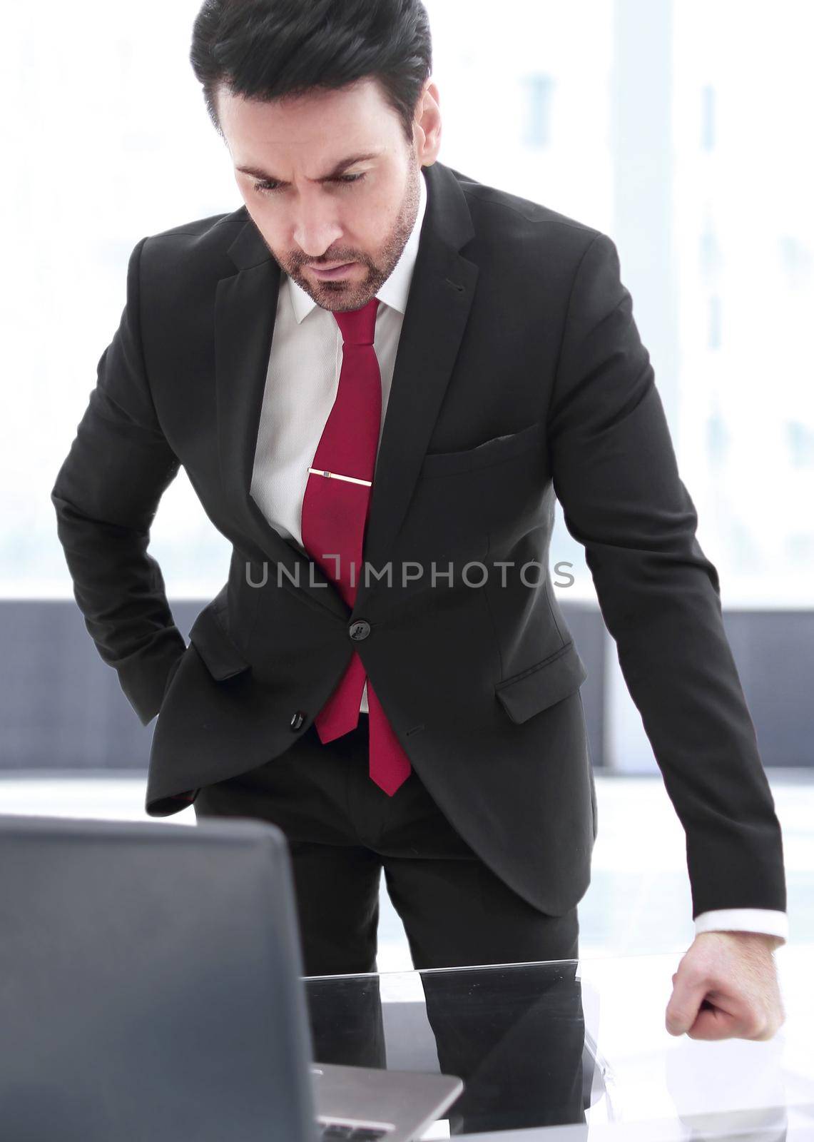 Businessman standing at his Desk and looking at the laptop screen.people and technology