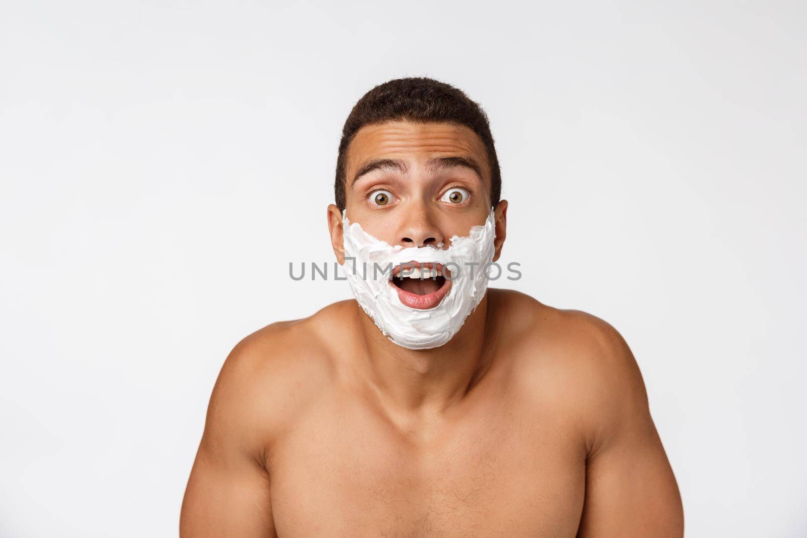 Close up of a happy naked african man with face in shaving foam isolated over gray background by Benzoix
