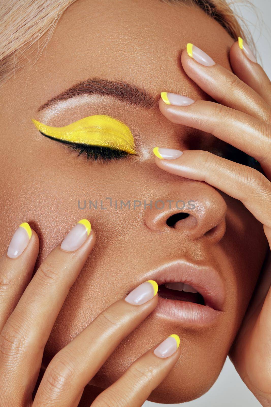 Beautiful close-up portrait of tanned skin woman. Sunburnt girl face with natural boho bronzed make-up and yellow manicure. Sexy summer style makeup