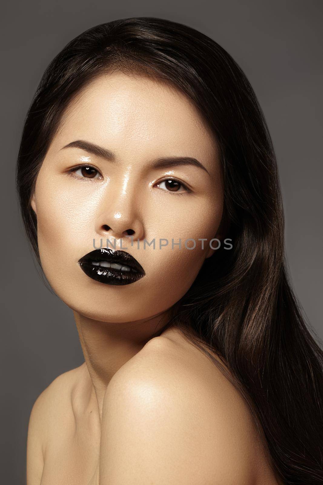 High Fashion Beauty Asian Model with bright Lip Gloss Make-up. Black Lips with gloss lipstick makeup. Long dark hair. Vertical photo