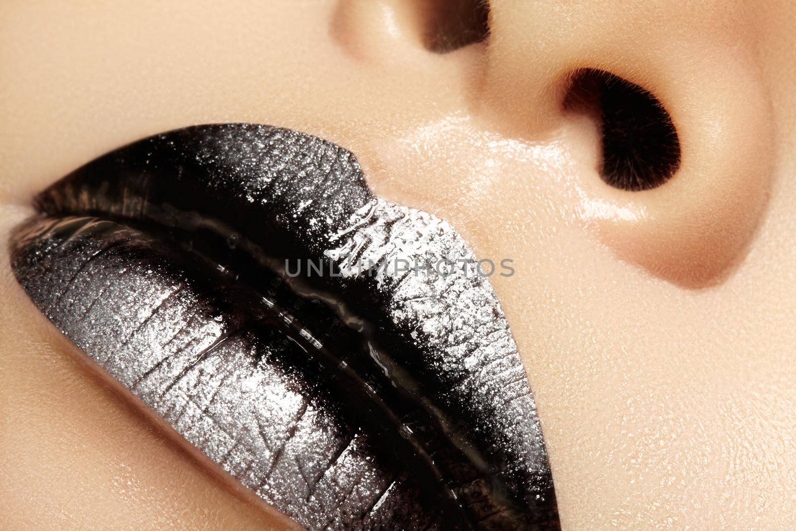 Macro close-up of female mouth. Sexy black Gloss Lips with silver glitter Makeup. Halloween Style Make-up with dark lipstick. Shiny celebrate visage