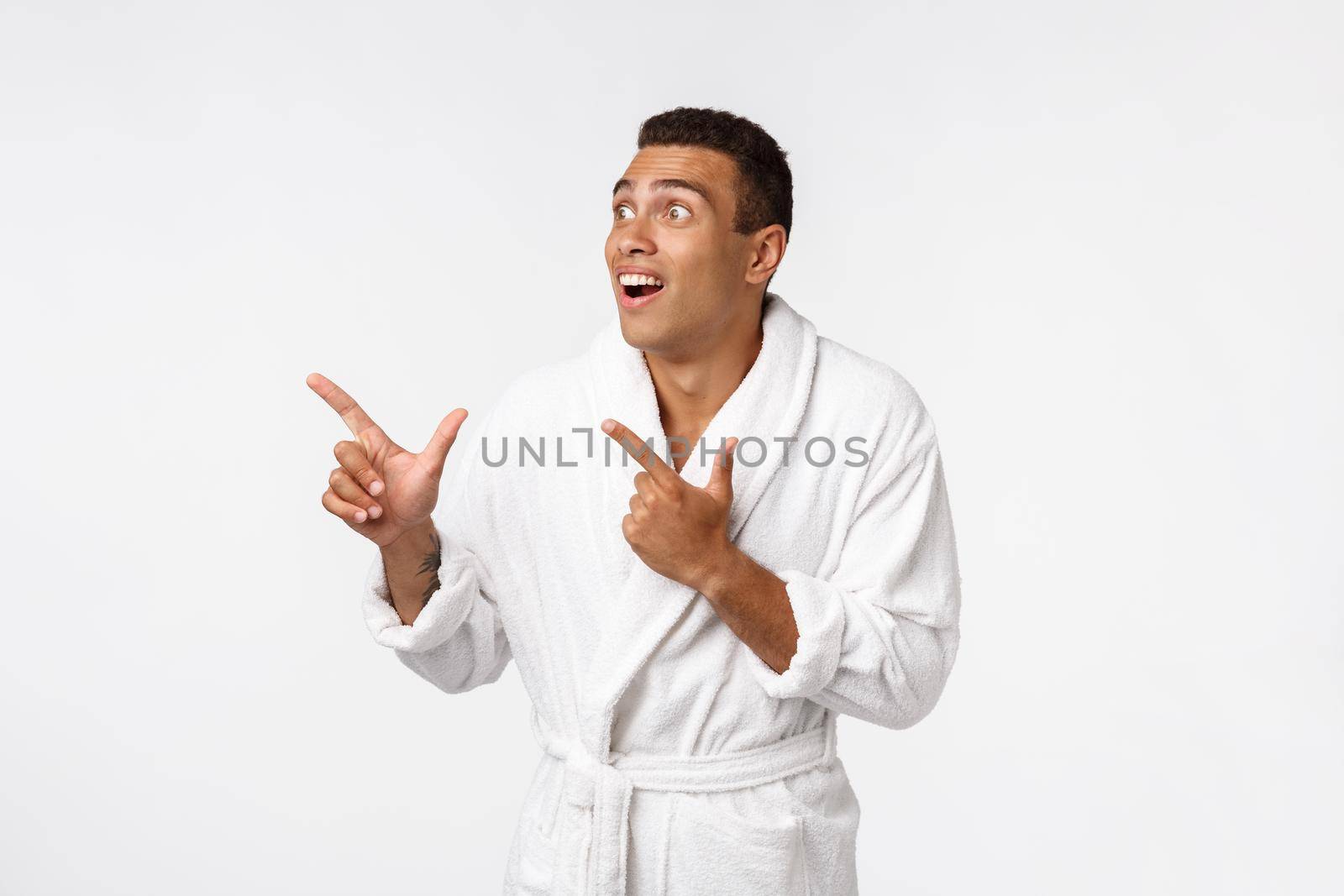 African american guy wearing a bathrobe pointing finger with surprise and happy emotion. Isolated over whtie background