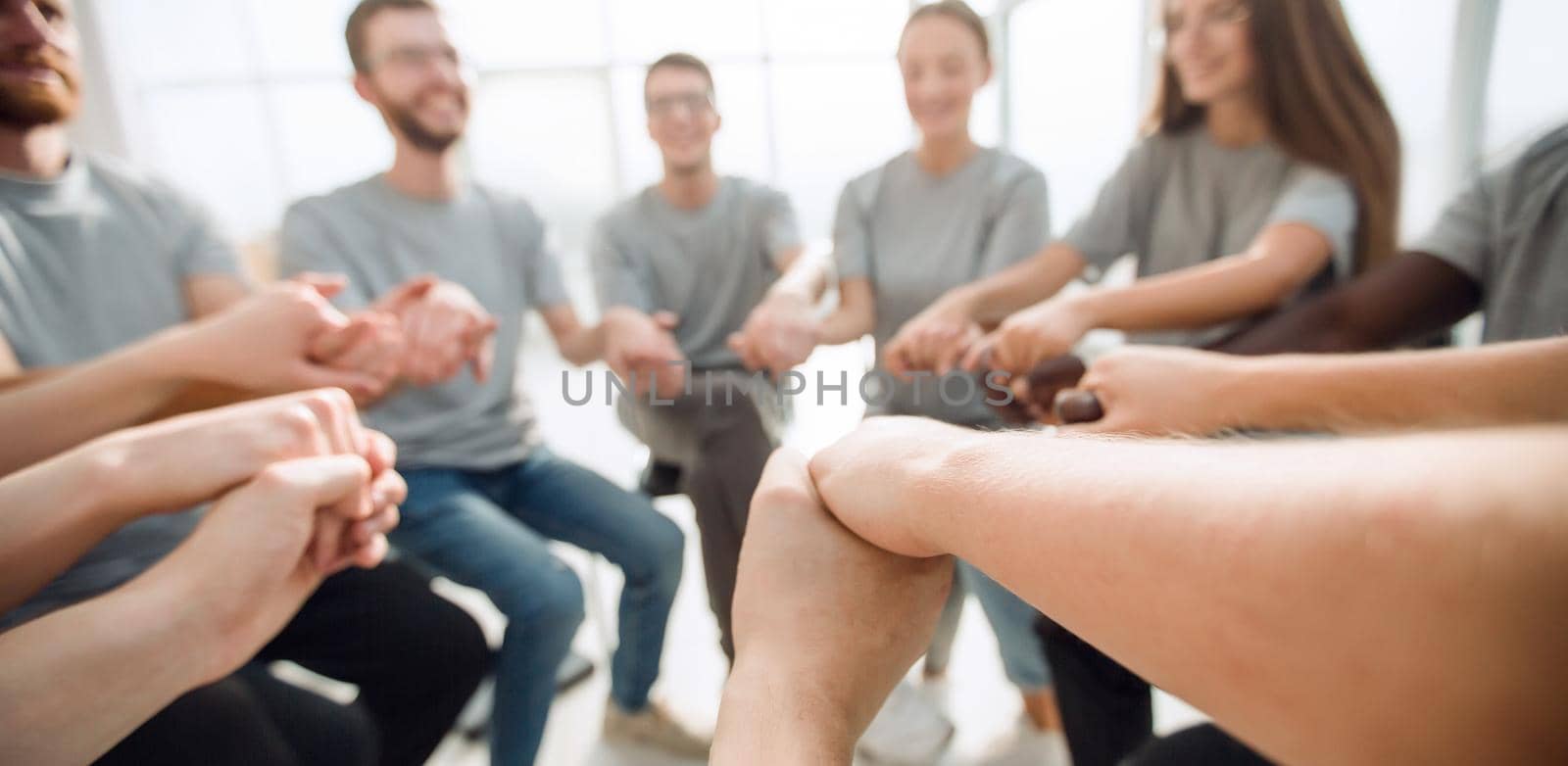 close up. a group of diverse young people holding hands by asdf