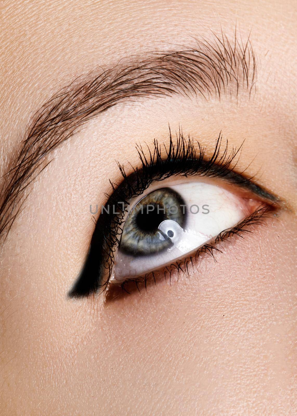 Beautiful macro shot of female eye with makeup. Perfect shape of eyebrows, blue eyeliner. Cosmetics and make-up.